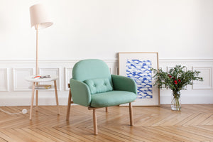 green armchair with oak legs and side table lamp