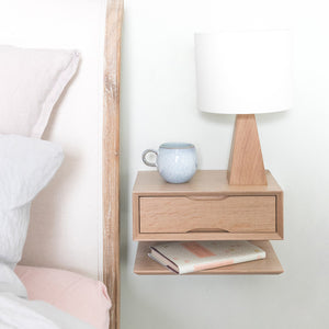 oak floating bedside table with lamp and bed